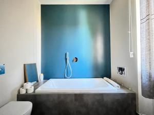 a bath tub in a bathroom with a blue wall at Maison Martina in Rivoli +30 photos