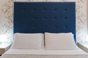 a bed with a blue headboard and two pillows at Hotel Welt in Gatteo a Mare