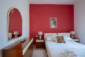 a bedroom with a red wall with a bed and a desk at Casa Miniera in Linopótis