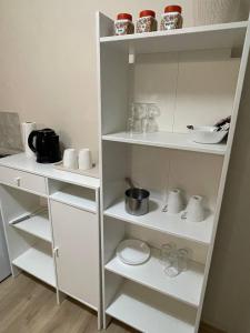 a white book shelf with cups and dishes on it at House1890 in Kula +12 photos