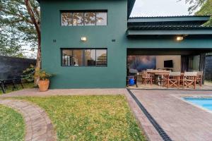 a green house with a patio and a swimming pool at Wild Villas in Victoria Falls