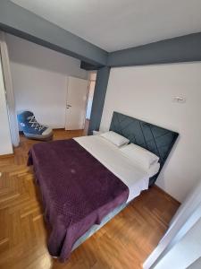 a bedroom with a large bed with a purple blanket at PENTHAUS apartment in Banja Luka