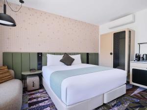 a bedroom with a large white bed and a chair at Novotel St Kilda in Melbourne