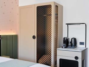 a room with a bed and a closet with a microwave at Novotel St Kilda in Melbourne