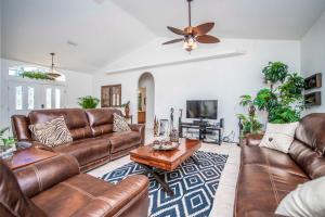 a living room with brown leather furniture and a ceiling fan at SWISS 56 - Lake Denise in Clermont