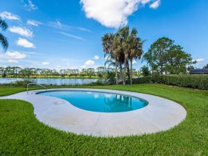 a swimming pool in the middle of a lawn with a lake at SWISS 14 - Lake Stephanie in Clermont