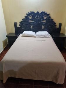 a bed with a large headboard with two pillows on it at Hotel Posada Aurorita in Villahermosa