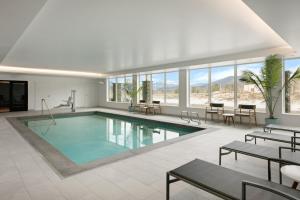 a swimming pool in a building with tables and chairs at Hotel Indigo North Conway by IHG in North Conway