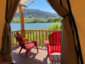 a deck with two chairs and a view of a lake at Ruby Glamping tent - tent site #9 in Klamath