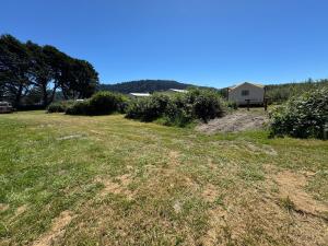 a field of grass with a house in the background at Ruby Glamping tent - tent site #9 in Klamath +3 photos