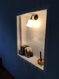 a light on a shelf with books and a candle at Ca' Boschetto in Bassano del Grappa