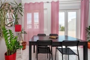 a dining room with pink curtains and a black table and chairs at Marine Freestyler Glorious Terrace in Faro