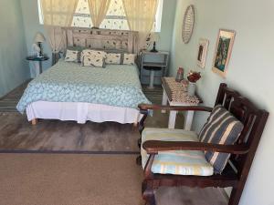 a bedroom with a bed and two chairs at Oceanview Sunrise Beach Villa in Rocklands