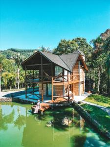 a house on a pond with a person sitting in the water at Refugio Poço do Cânion in Alfredo Wagner
