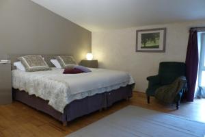 a bedroom with a bed and a green chair at La Mouline de Belin in Lectoure