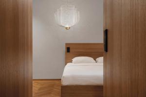 a bedroom with a white bed and a chandelier at Woodline Suite in Luxembourg