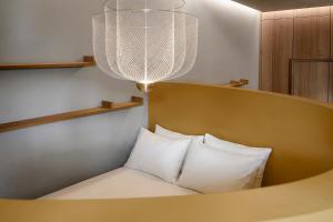a bed with white pillows and a chandelier at Woodline Suite in Luxembourg