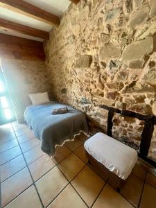 a bedroom with a bed and a stone wall at The Pilgrim Stone - Vegan B&B in Rabanal del Camino