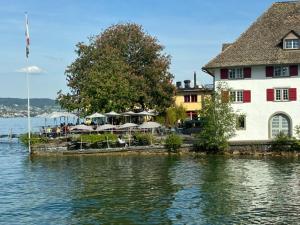 a building with tables and umbrellas next to the water at Haus Enisa in Horgen