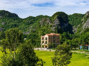 a building in a field with mountains in the background at Tam Coc Haven House in Ninh Binh