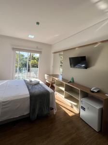 a bedroom with a bed and a desk with a television at Hotel Pasqualotto in Chopinzinho