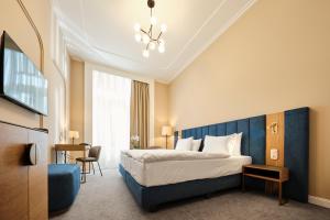 a hotel room with a bed with a blue headboard at Palatinus Grand Hotel in Pécs