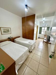 a hotel room with two beds and a television at Hotel Minas Palace in Passos +37 photos