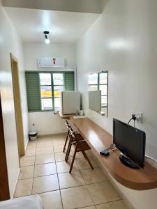 a room with a desk with a television on it at Hotel Minas Palace in Passos