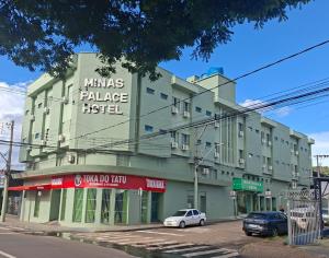 a green building with a white car parked in front of it at Hotel Minas Palace in Passos