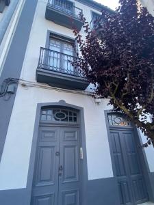 a white building with a blue door and a balcony at Apartamento en Monforte estación de tren in Monforte de Lemos