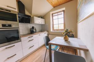 a kitchen with white cabinets and a table with chairs at Apartman Susilova Slavkov in Slavkov u Brna +25 photos