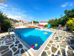a swimming pool with blue water and rocks at Nice house close to the sea in Mati