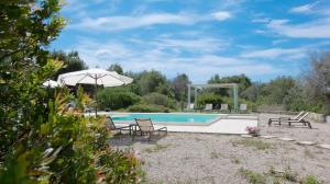 an outdoor pool with an umbrella and chairs and a table at Borgo del Sole Salento in Torre Vado