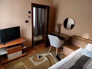 a bedroom with a bed and a desk with a television at Casa Anomis in Călimăneşti