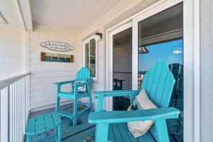a pair of blue chairs and a table on a porch at Hotel condo features beach access shared pool - near town in Fort Morgan