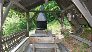 an outdoor grill in a wooden shelter with a table and a bench at Chata Huslenky in Huslenky +17 photos