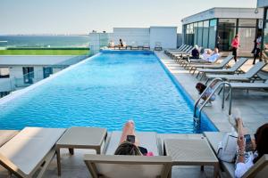 people laying on chairs in front of a pool on a building at INFINITY Sea View Luxury SUITE in Mamaia Sat/Năvodari +10 photos