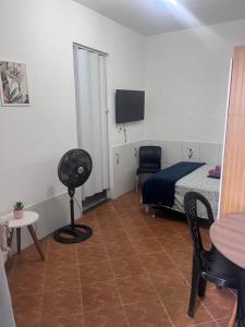 a bedroom with a bed and a table and a chair at Kitnet aconchegante in Pedra de Guaratiba