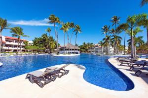 una piscina en un complejo con sillas y palmeras en Occidental Punta Cana - All Inclusive, en Punta Cana