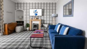 a living room with a blue couch and a table at Modern Apartment with Garden in Rothesay