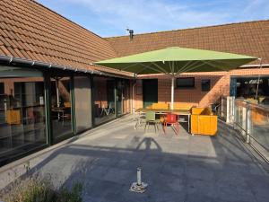 a patio with a green umbrella and tables and chairs at Vakantie verblijf in Bredene