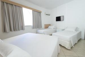 a hotel room with two beds and a television at Hotel Ilha da Madeira in Balneário Camboriú