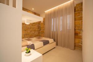 a bedroom with a bed and a brick wall at DaiRa 103 Luxury Suite sulle Mura di Cefalù in Cefalù