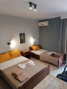a bedroom with two beds with yellow pillows at Hotel Manos in Paralia Katerinis