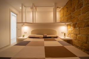 a bedroom with a bed and a brick wall at DaiRa 103 Luxury Suite sulle Mura di Cefalù in Cefalù +27 photos