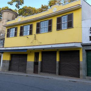 a yellow building with four garage doors on a street at Apt Petrópolis - Imperial in Petrópolis