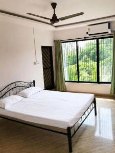 a bedroom with a bed with white sheets and windows at Attra Farms in Karjat +29 photos