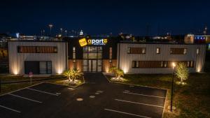 a parking lot in front of a store at night at APARTÉ HOTEL Dijon Sud in Chenôve