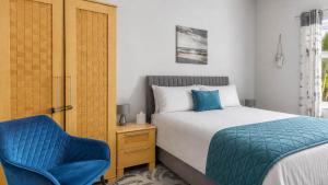 a bedroom with a bed and a blue chair at Modern Apartment with Garden in Rothesay +11 photos