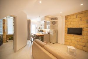 a living room with a couch and a stone wall at DaiRa 103 Luxury Suite sulle Mura di Cefalù in Cefalù
